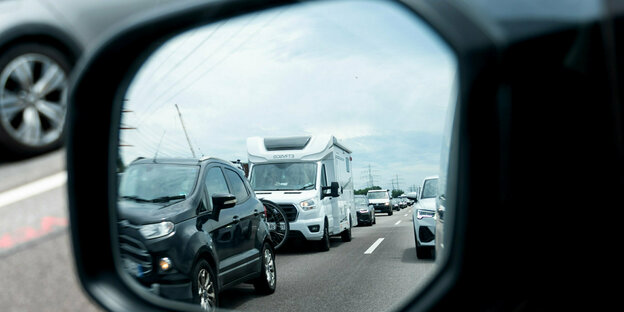 Stau auf der Autobahn - im Seitenspiegel ist ein Caravan und ein SUV zu sehen Stau auf der Autobahn - im Seitenspiegel ist ein Caravan und ein SUV zu sehen