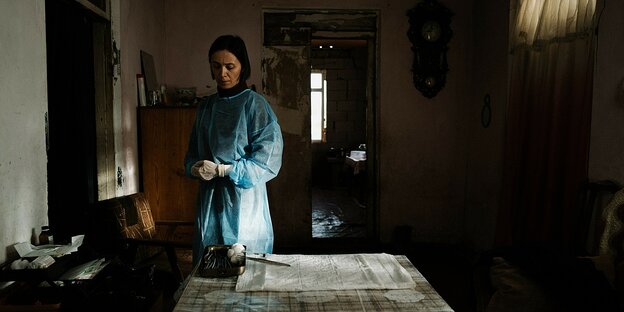 Eine Frau in medizinischer Schutzkleidungsteht in einem dunklen Zimmer. Eine Frau in medizinischer Schutzkleidungsteht in einem dunklen Zimmer.