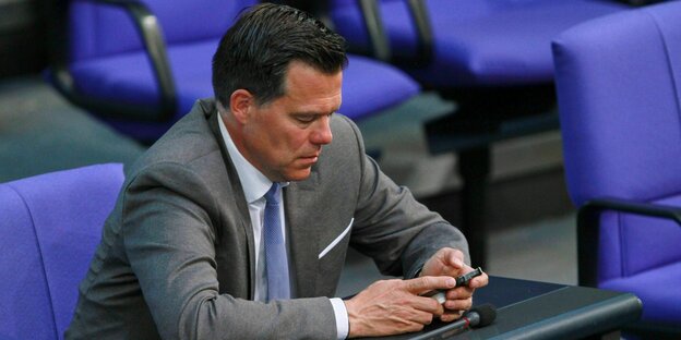 Gero Hocker sitzt im Bundestag undspielt mit seinem Smartphone Gero Hocker sitzt im Bundestag undspielt mit seinem Smartphone