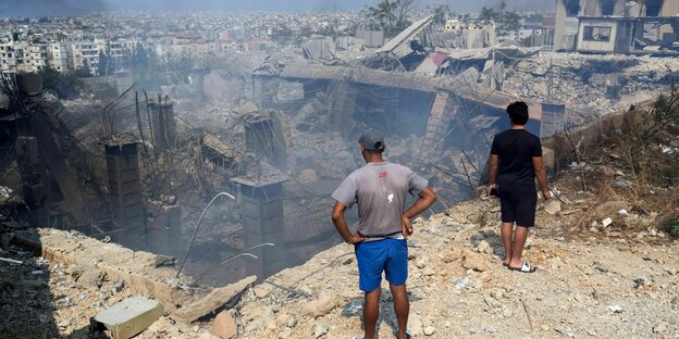 Männer stehen vor zerbombtem Haus Männer stehen vor zerbombtem Haus
