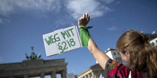 Eine Frau hält ein Schild in die Höhe: Weg mit Paragraph 218 und einen Kleiderbügel, das Symbol für illegale Abtreibungen Eine Frau hält ein Schild in die Höhe: Weg mit Paragraph 218 und einen Kleiderbügel, das Symbol für illegale Abtreibungen