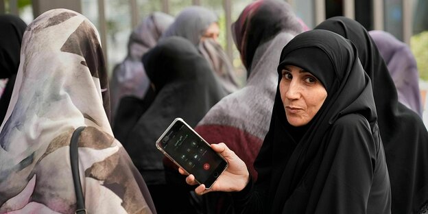 Eine Frau im Tschador hält ein Mobiltelefon in den Händen Eine Frau im Tschador hält ein Mobiltelefon in den Händen