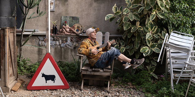 Ein Mann mit Ukulele sitzt verträumt auf einem Stuhl. Ein Mann mit Ukulele sitzt verträumt auf einem Stuhl.