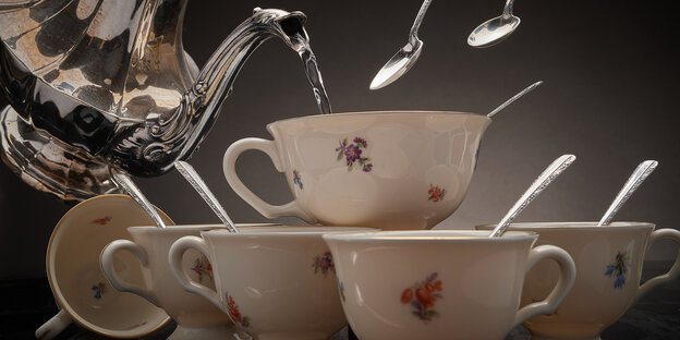 Elegante Teetassen werden mit heißem Wasser aus einer silbernen Teekanne befüllt. Elegante Teetassen werden mit heißem Wasser aus einer silbernen Teekanne befüllt.