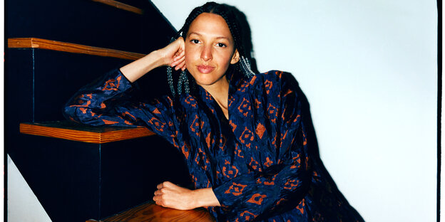 Nala Sinephro sitzt auf einer Holztreppe Nala Sinephro sitzt auf einer Holztreppe