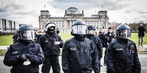 Polizisten in Uniform und mit Schutzhelmen stehen vor dem Reichstag in Berlin Polizisten in Uniform und mit Schutzhelmen stehen vor dem Reichstag in Berlin