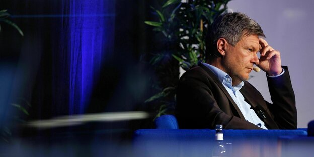 Robert Habeck sitzt nachdenklich schauend in einem Sessel und hört zu Robert Habeck sitzt nachdenklich schauend in einem Sessel und hört zu