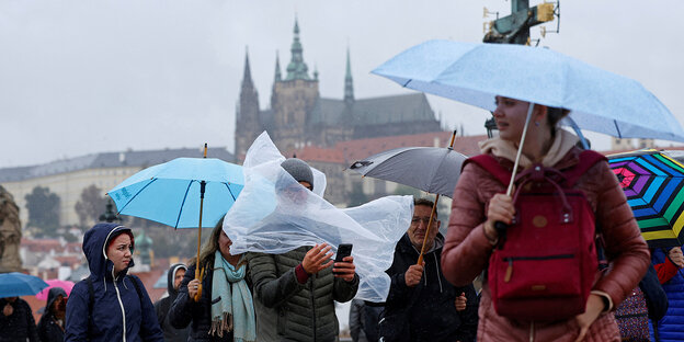 Menschen mit Regenschirmen auf der Karlsbrücke in Prag Menschen mit Regenschirmen auf der Karlsbrücke in Prag