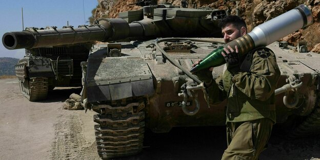 Ein israelischer Reservesoldat trägt eine Panzergranate in einem Panzerkampfgebiet nahe der nordisraelischen Grenze zum Libanon Ein israelischer Reservesoldat trägt eine Panzergranate in einem Panzerkampfgebiet nahe der nordisraelischen Grenze zum Libanon