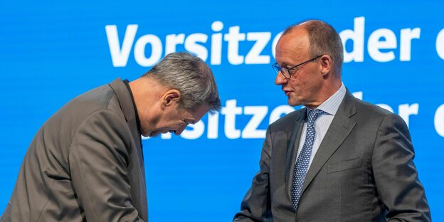 Markus Söder verbeugt sich vor Friedrich Merz. Sie reichen sich dabei die Hand. Markus Söder verbeugt sich vor Friedrich Merz. Sie reichen sich dabei die Hand.