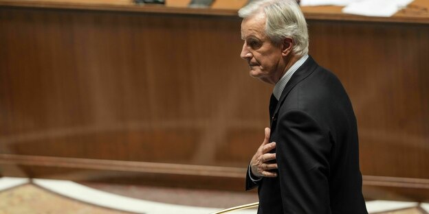 Ein Mann hält sich die Hand an die Brust und läuft zu einem Rednerpult in der Nationalversammlung Frankreichs Ein Mann hält sich die Hand an die Brust und läuft zu einem Rednerpult in der Nationalversammlung Frankreichs