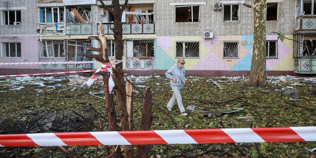 Eine Frau vor einer zerstörten Hausfassade Eine Frau vor einer zerstörten Hausfassade