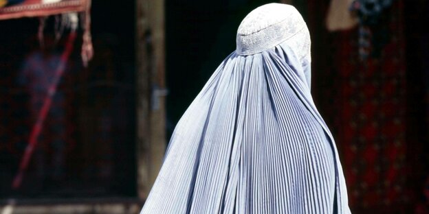 Eine Frau trägt eine Burka. Sie ist von hinten zu sehen Eine Frau trägt eine Burka. Sie ist von hinten zu sehen