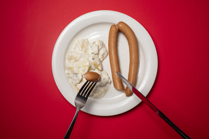 Ein Teller mit Kartoffelsalat und Würstchen.