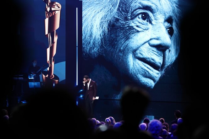 Igor Levit auf der Bühne vor einem Foto von Margot Friedländer