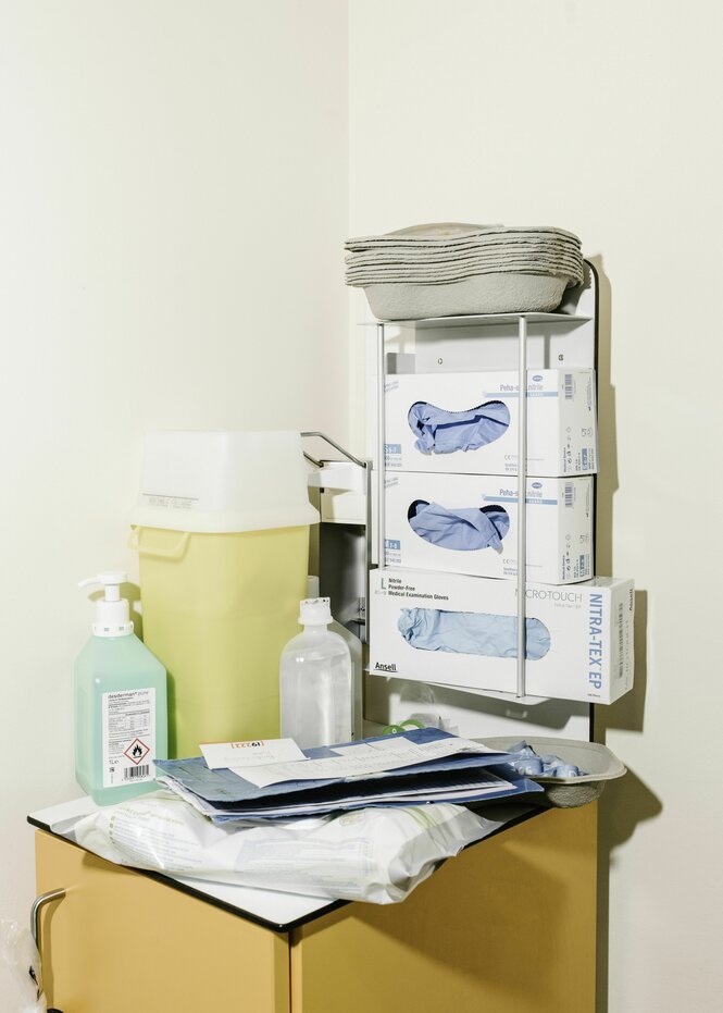 Vor einem Krankenzimmer sind Schutzmaterialien für das medizinische Personal bereitgestellt