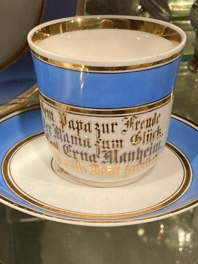 Eine blau-weiße Sammeltasse mit goldenen Buchstaben in altdeutscher Schrift